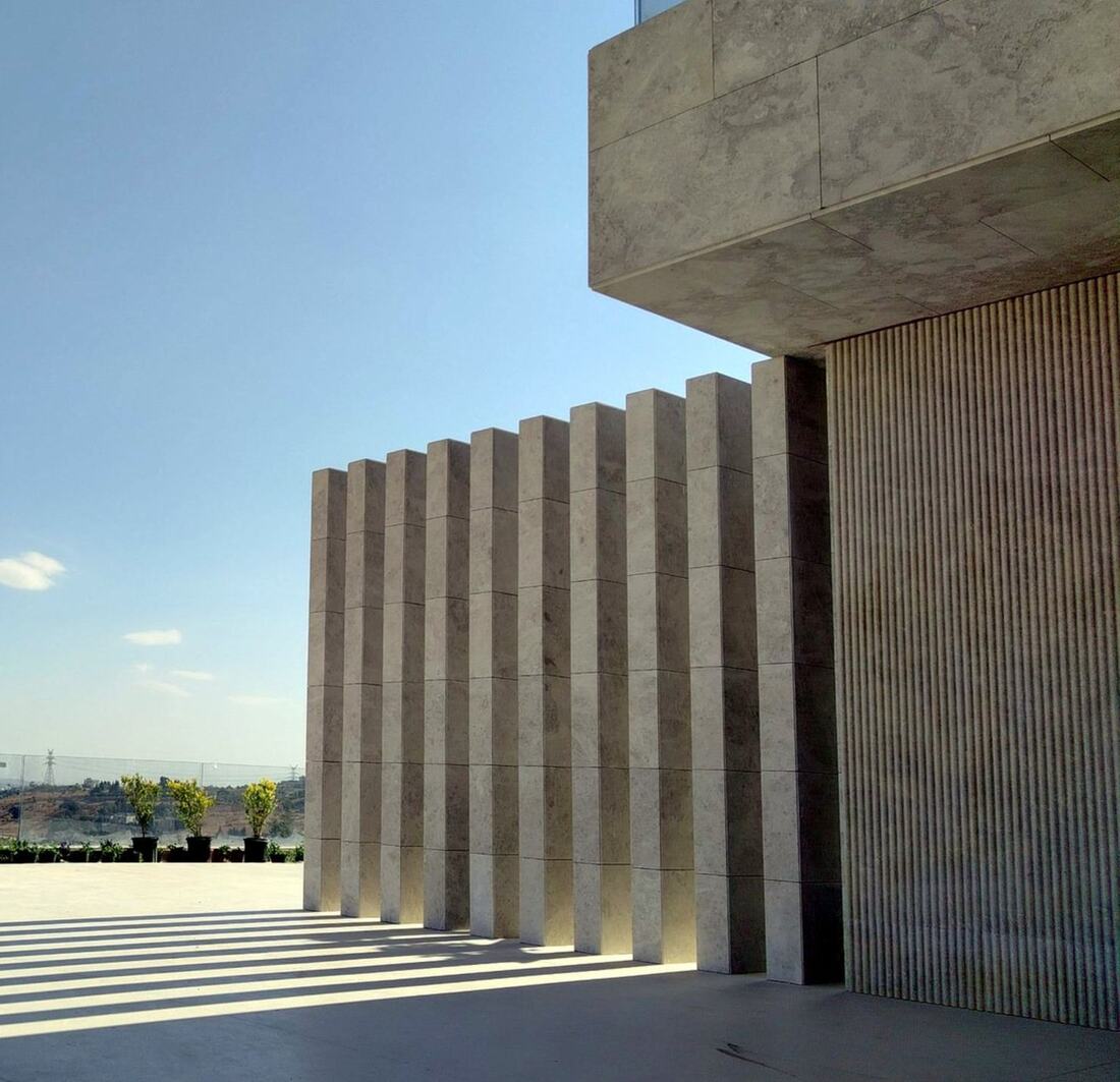 Vertical natural-stone fins on a villa façade